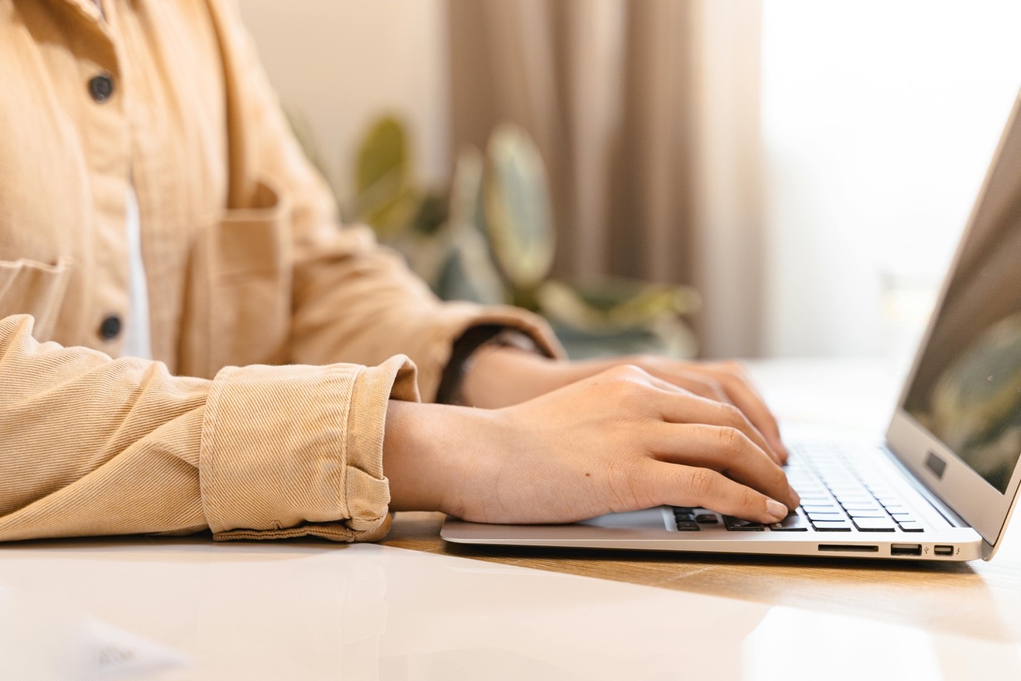 Close-up of person's hands typing on laptop keyboard.